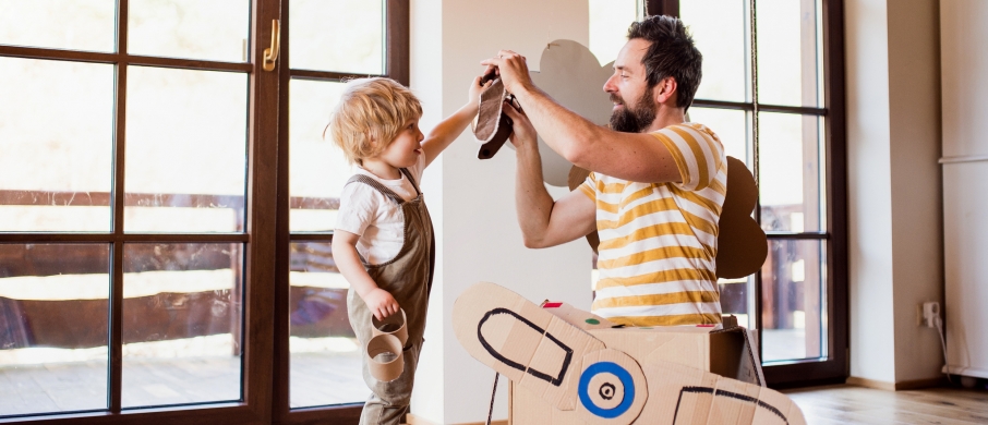 Father and son playing with toys inside house