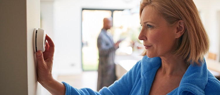 woman adjusting thermostat